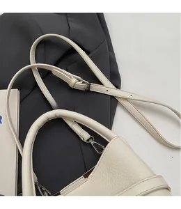 Close-up of litchi pattern leather texture and silver hardware on cream bucket bag