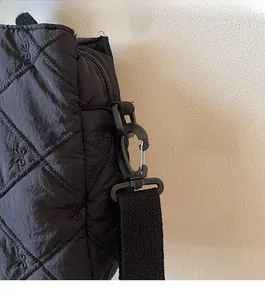 Detail of black quilted tote bag with bow embroidery and durable shoulder strap hook
