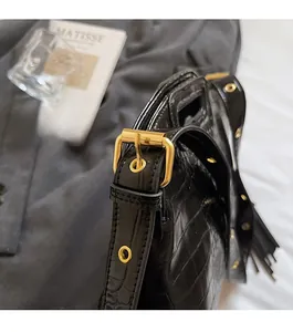 Close-up of black crocodile embossed leather strap with polished gold-tone hardware