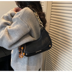 Detail of black crescent shoulder bag with golden chain strap and wooden bead charm