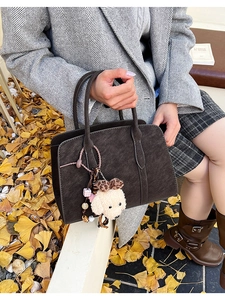 Détail d'un sac cabas marron rétro avec un pendentif chiot en peluche et une texture mate