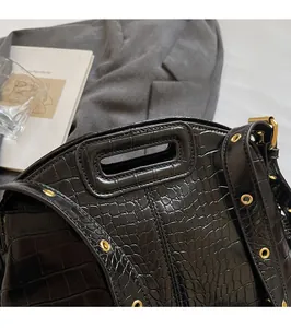 Close-up of black crocodile-embossed leather texture and rectangular cutout handle