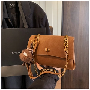 Close-up of vintage brown shoulder bag with gold chain strap, twist lock, and plush charm
