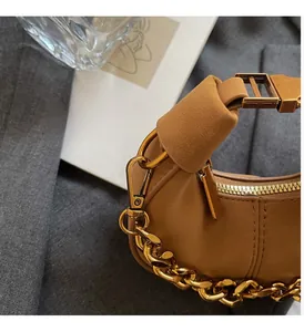 Gros plan sur le sac hobo en cuir marron avec grainage et chaîne dorée brillante détaillée
