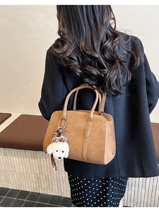 Détail d'un grand sac cabas vintage marron avec pendentif chien en peluche et poignées robustes
