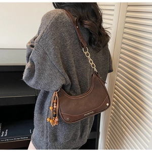 Detail of coffee brown leather half-moon bag with gold chain and beaded tassel charm