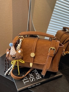 Bolso retro marrón de ante con cierre dorado, asa superior y colgante de osito mono