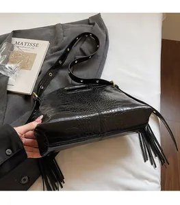 Detail of black crocodile pattern shoulder bag with long side tassels and metal eyelets