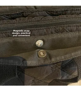 Close-up of silver magnetic clasp and zipper on black quilted nylon tote bag