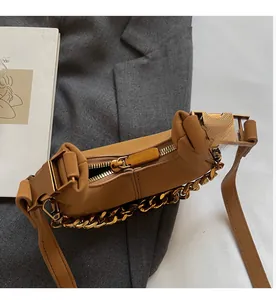 Détail de la fermeture éclair du sac marron avec chaîne dorée sur veste grise