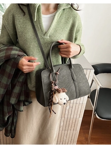 Détail du sac bandoulière olive foncé avec charm chiot en peluche et texture cuir mat