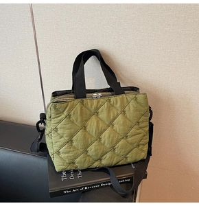 Close-up of green quilted shoulder bag with dual silver zippers and adjustable black strap