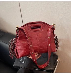 Detailed view of wine red crocodile pattern leather with long bohemian fringe texture