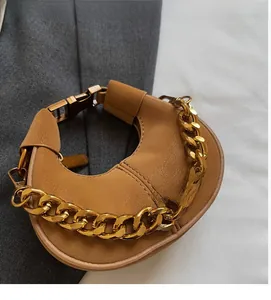 Détail du sac lune en cuir marron avec grosse chaîne dorée et fermoir en métal