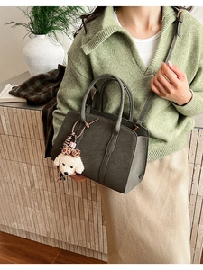 Détail d'un grand cabas vintage en cuir vert foncé avec breloque chien sur le modèle
