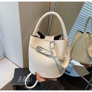 Detail of off-white bucket bag featuring premium lychee grain texture and silver buckle