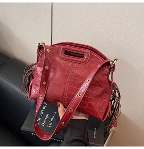 Close-up of crocodile textured wine red shoulder bag with stylish tassel accents