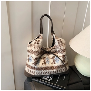 Detail of knit tote bag with snowflake pattern and brown leather bow ribbon handle