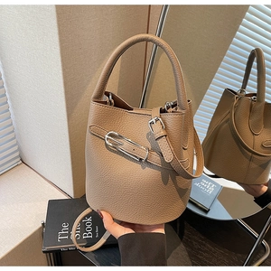 Detail of light coffee bucket bag showing premium lychee texture and buckle strap