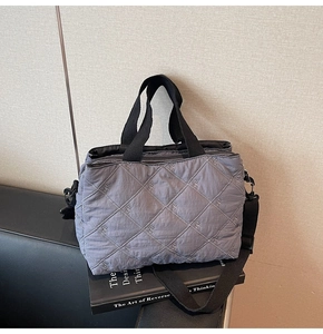 Macro detail of grey quilted nylon bag with delicate bow embroidery and adjustable strap