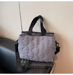Detail of grey quilted shoulder bag with bow embroidery and adjustable black strap