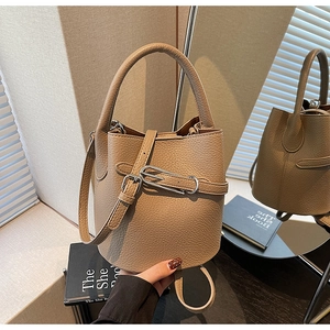 Detail of lychee pattern leather bucket bag with silver buckle and decorative strap