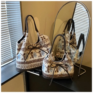 Detail of Nordic snowflake jacquard plush tote bags with brown bow accents and faux leather trim