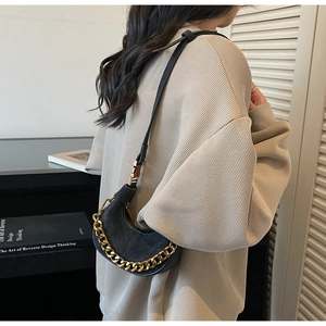 Détail du sac demi-lune noir avec chaîne dorée épaisse porté par un mannequin