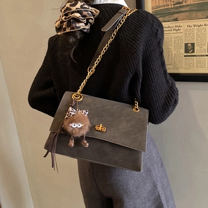 Detailed view of gray matte leather tote with golden db lock and plush monster charm