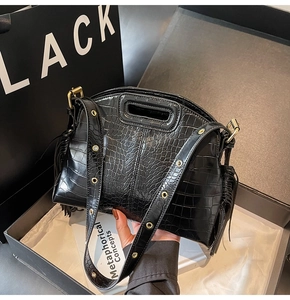 Detail of black croc-embossed leather tote with long fringes and metal eyelet shoulder strap