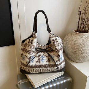 Retro ethnic style knitted tote bag with blue snowflake patterns on a travel suitcase