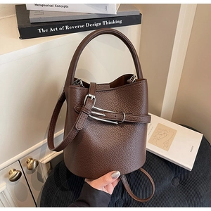 Close-up of deep brown lychee grain leather bucket bag with silver buckle and hand strap