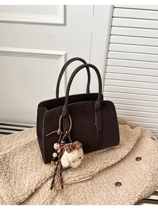 Gros plan sur un sac cabas en cuir marron foncé avec un charmant pendentif chiot