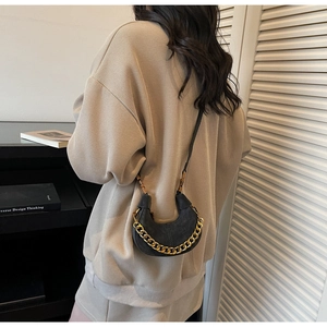 Detail of a black mini crescent bag with chunky gold chain and leather strap