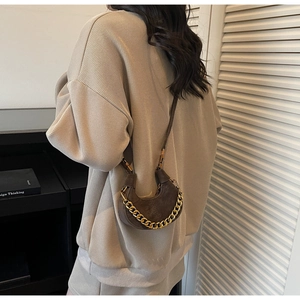 Detailed view of brown crescent bag featuring chunky gold chain and retro leather texture