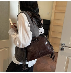 Detailed macro view of dark brown faux crocodile skin texture and fringe on shoulder bag