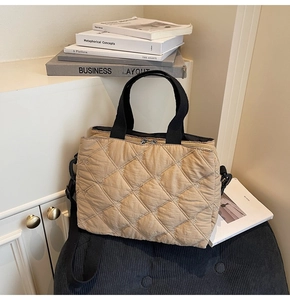 Close-up of quilted nylon tote with white bow embroidery and black woven straps