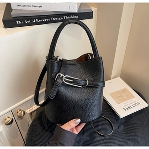 Macro detail of black litchi grain leather bucket bag with silver metal buckle
