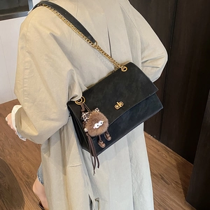 Detail of black suede shoulder bag featuring a gold square lock and chunky chain strap