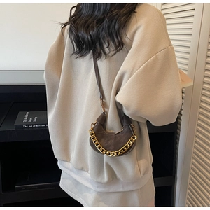 Détail du sac croissant marron foncé avec chaîne dorée et texture en cuir