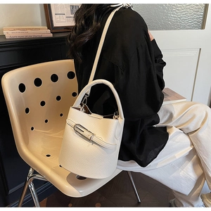 Detailed macro view of white pebble leather texture and metallic buckle on bucket bag