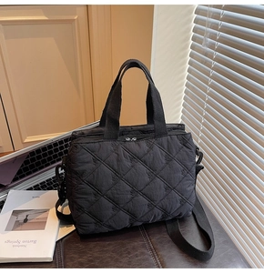 Detail of black quilted crossbody bag with embroidery on a professional desk