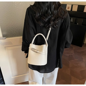 Close-up of cream leather bucket bag texture with adjustable strap and handle