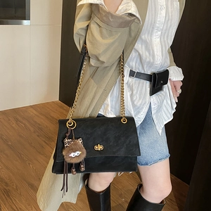 Detail of black suede chain bag with golden lock and leopard plush charm accessory