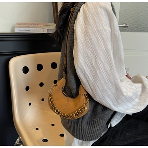 Sac bandoulière demi-lune en cuir marron avec chaîne dorée dans un décor de style de vie