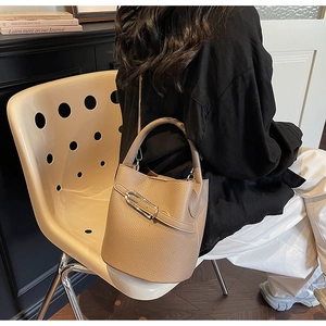 Detail of khaki leather bucket bag with metal buckle on a beige designer chair