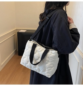 Detail of white quilted tote bag featuring black contrast straps and diamond stitching