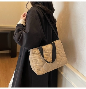 Detailed quilted rhombus texture on a khaki tote bag with black shoulder straps