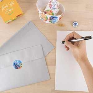 Floral and animal 'Thank You' stickers roll on desk for gift sealing and decoration