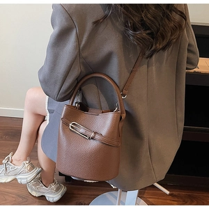 Detailed view of brown lychee grain leather bucket bag with silver buckle and shoulder strap